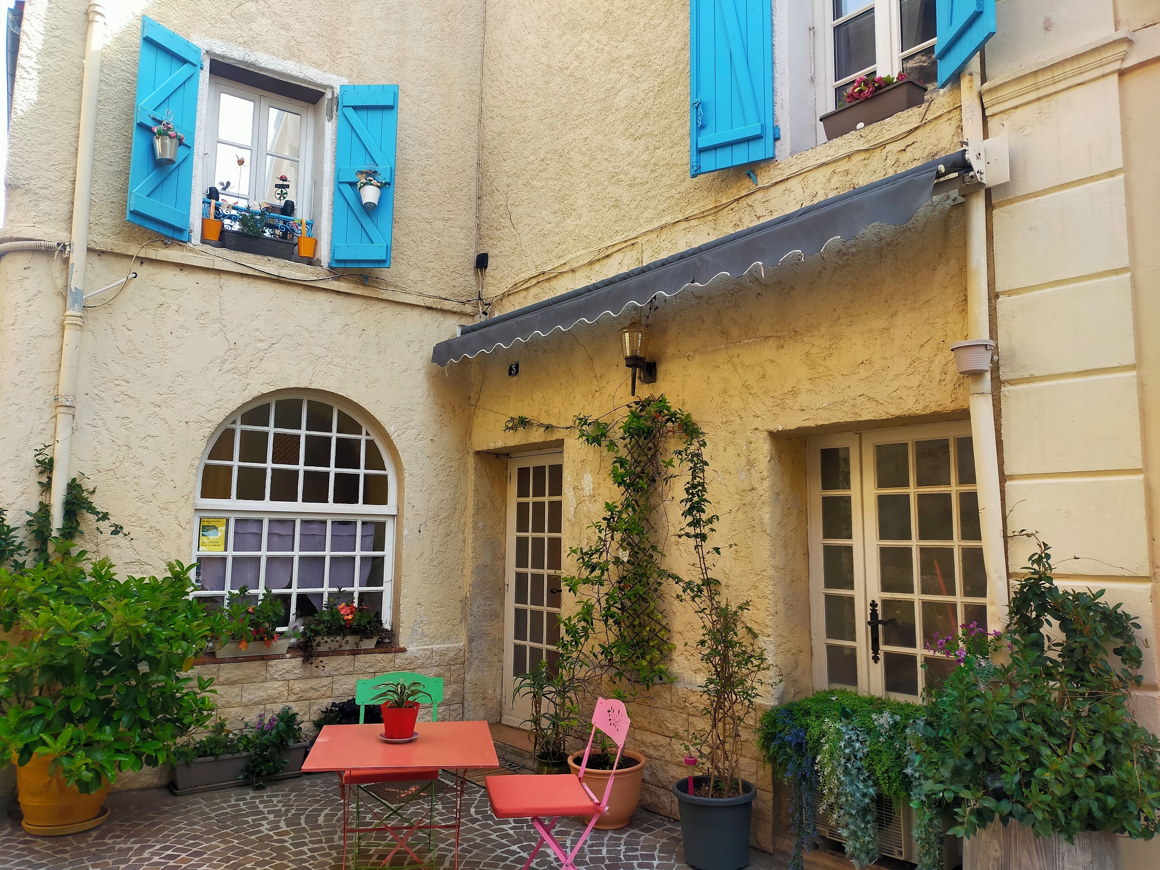 Ein Innenhof mit Tisch und Stühlen, Blumentöpfen und einer kleinen Gartenanlage.