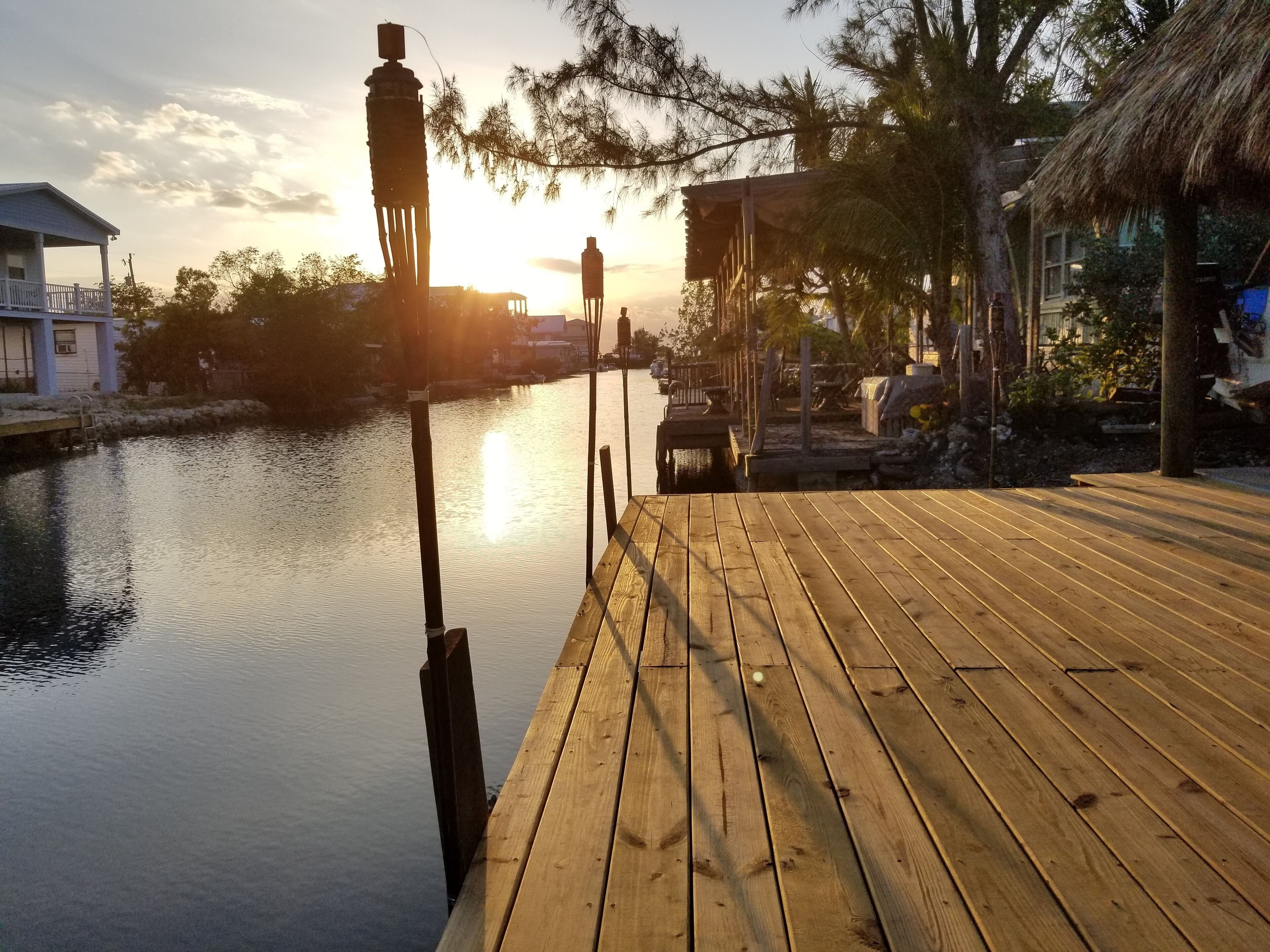 A wooden dock extending into calm water with a sunset in the background.