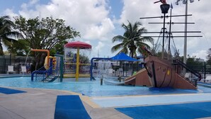 Un parque acuático con piscina, toboganes y una estructura con forma de barco pirata.