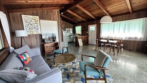A cozy living area with a sofa, armchairs, a coffee table, and a dining table. A kitchen is visible in the background. - Secluded Ocean View Mid-Century Modern Retreat  (Fort Bragg)