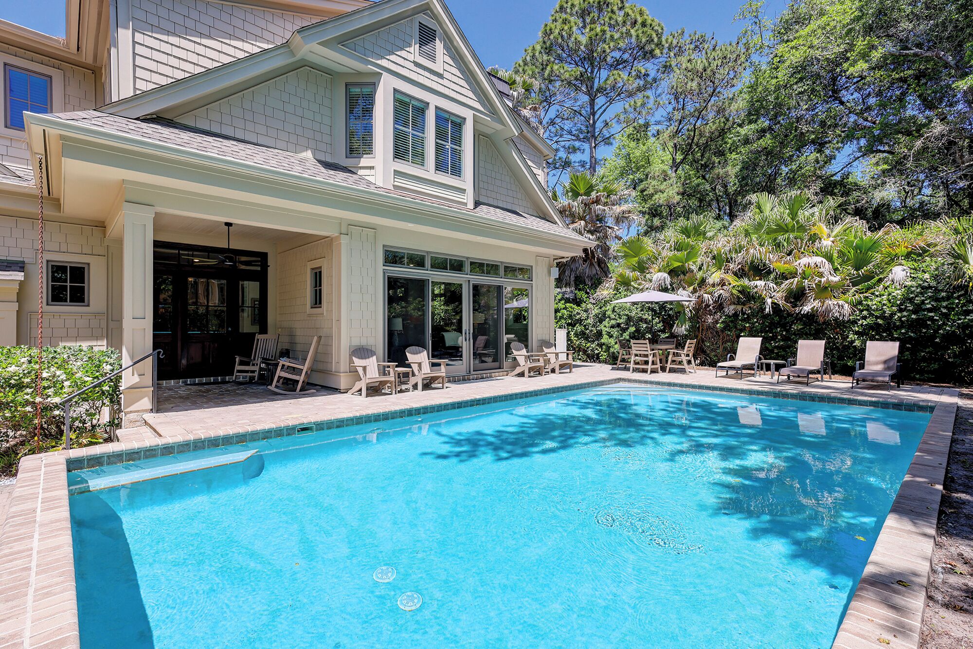 Ein Haus mit Swimmingpool, Gartenmöbeln und einer überdachten Terrasse.