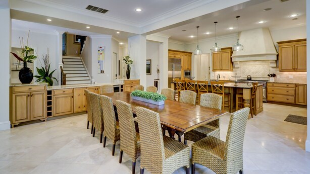Una cocina amplia con armarios de madera, una isla central y un comedor con sillas de mimbre.