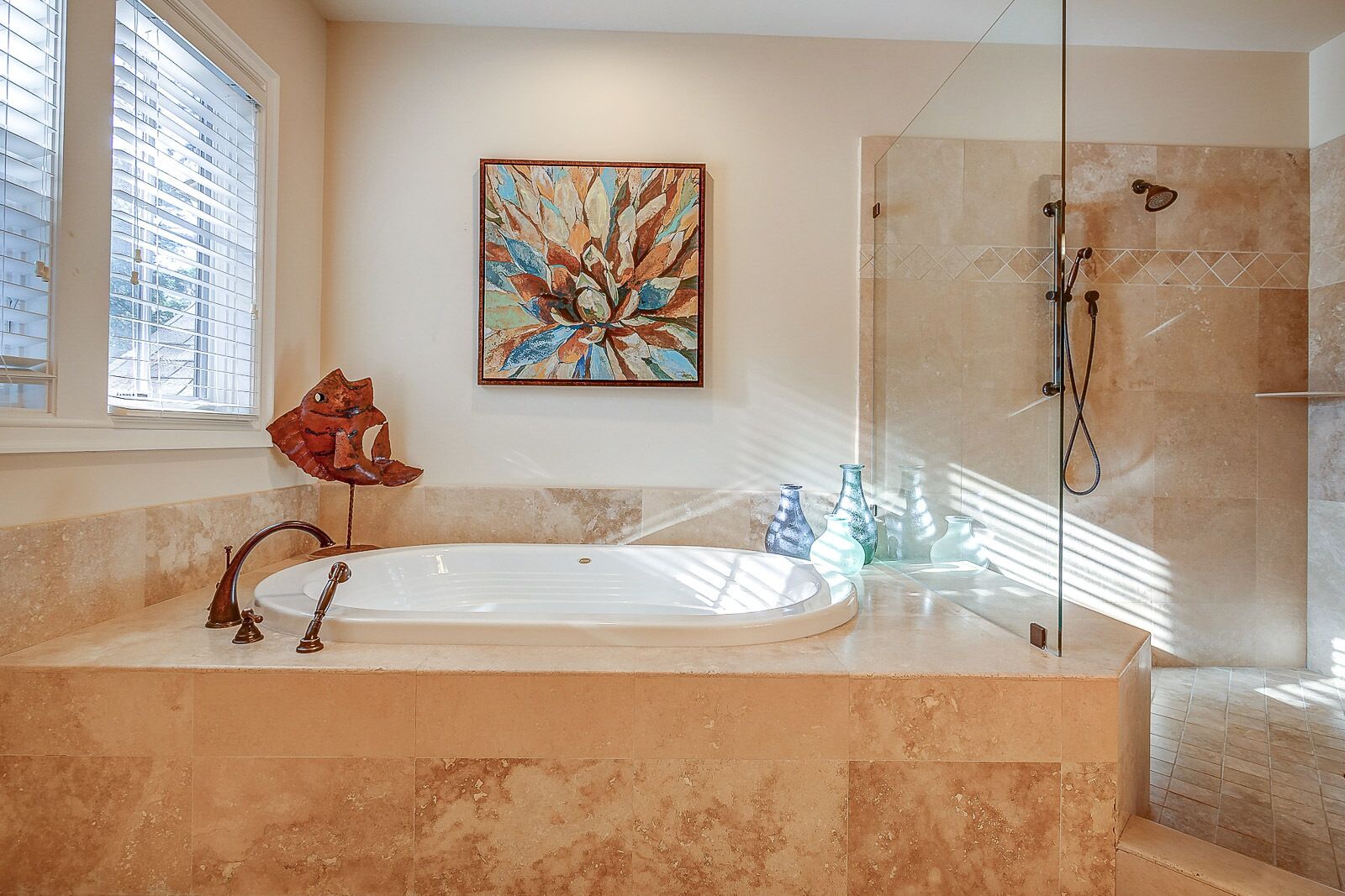 A bathroom with a freestanding bathtub, a glass shower enclosure, and a large window with blinds.