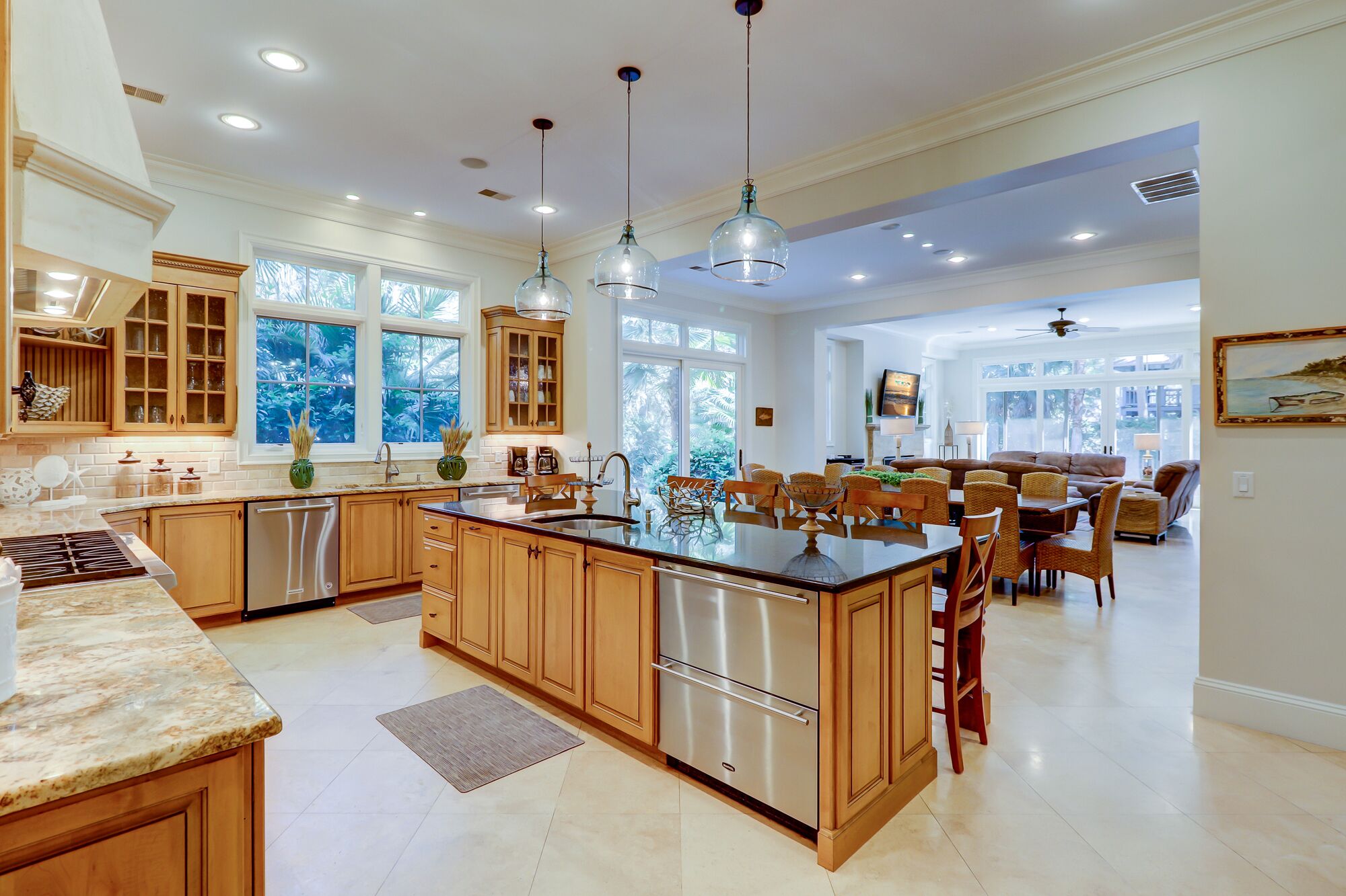 A spacious kitchen with wooden cabinets, a large island, and pendant lighting.