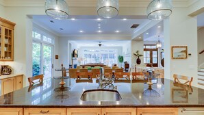 Una cocina amplia con una isla grande, armarios de madera e iluminación colgante.