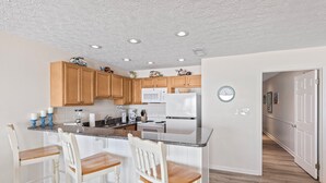 A kitchen with wooden cabinets, a white refrigerator, and a granite countertop. - 26- Your vacation starts here in this FAMILY FRIENDLY condo that sleeps 6! (Destin)