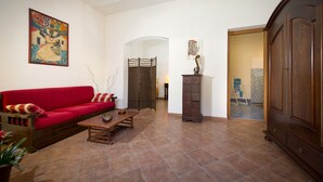 A living room with a red sofa, a wooden coffee table, a cabinet, and a decorative wall hanging. - THE SUN OF SICILY SEA VIEW.  WIFI FREE. WHOLE HOUSE. (Castellammare del Golfo)