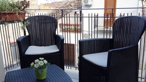 Two wicker chairs with cushions on a balcony with a tiled floor and a small table with a flower pot. - THE SUN OF SICILY SEA VIEW.  WIFI FREE. WHOLE HOUSE. (Castellammare del Golfo)