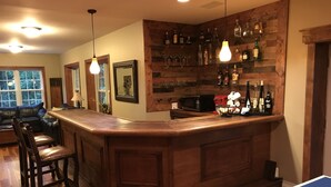 Un espace bar avec des lambris en bois, une table de ping-pong et un coin salon avec un canapé et des fauteuils.