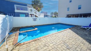 Una piscina circondata da una recinzione bianca, con una scala per accedervi e un patio in mattoni.