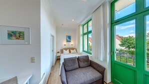 Un dormitorio con cama, sofá y ventanas amplias con cortinas.