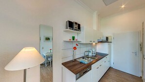 Una cocina compacta con armarios blancos, una encimera de madera y un microondas.