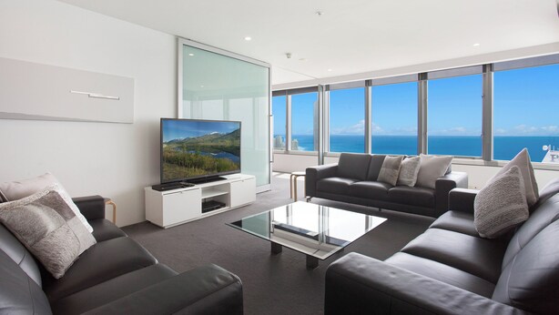Una sala de estar moderna con un televisor de pantalla plana grande, dos sofás y una mesa de centro.