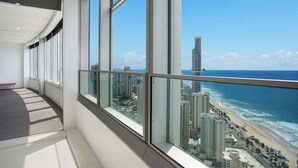 Interior moderno de un hotel con amplias ventanas que ofrecen vistas a una playa y edificios altos.