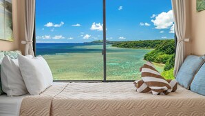 A room with a large window offering a view of a tropical beach and ocean.