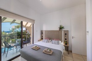 A hotel room with a balcony, a bed with a headboard, and a small bedside table with a plant. - Villa Mylos 7 is located in the absolute center of Protaras (Protaras)