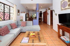 A living room with a sofa, coffee table with fruit, and a TV stand.