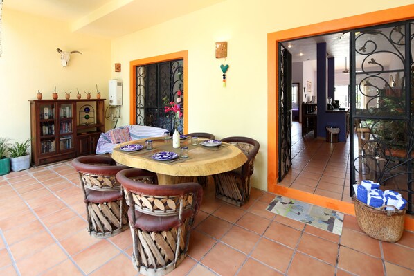 A dining area with a round wooden table, six wooden chairs, and a buffet table with food items.