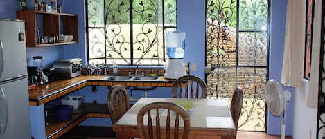 Enjoy meals in the kitchen with a dining area featuring a refrigerator, toaster, blender, and water dispenser. The space includes a table and chairs.