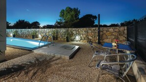 Un espace piscine agrémenté d’un mur en pierre, d’un jacuzzi et de mobilier d’extérieur.