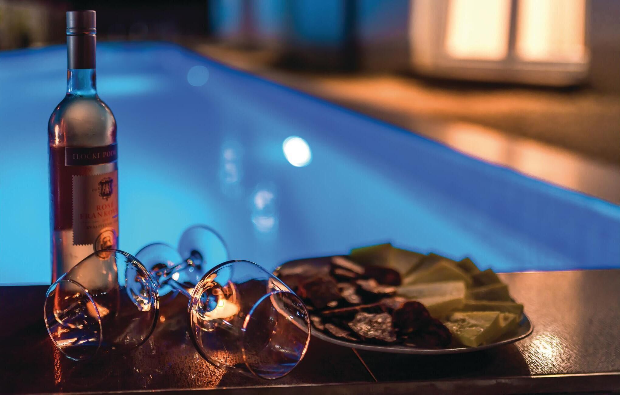 A bottle of Hocki Pod Rosi Franke on a bar counter with glasses and a plate of food.