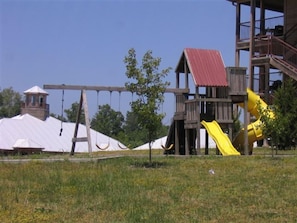 Children can play on the playground structure featuring a playhouse, slide, and swing set.