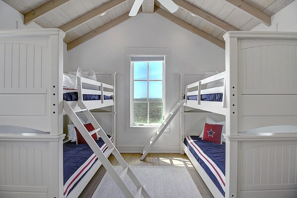 A room with two bunk beds, a window, and a sloped ceiling.