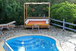 Un espace piscine agrémenté d’une chaise suspendue en bois, d’une petite table et d’une clôture blanche.