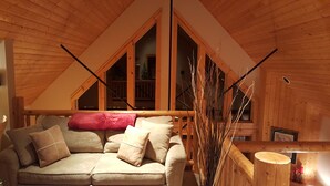A cozy room with a wooden ceiling, a sofa with cushions, and a window with a view of the outside. - Luxurious 3BR/2BA Eagle Crest Chalet on Golf Course w/ Private Hot Tub & Garage (Redmond)