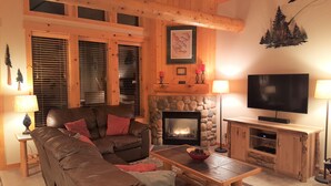 A cozy living room with a fireplace, a television, and a comfortable sofa. - Luxurious 3BR/2BA Eagle Crest Chalet on Golf Course w/ Private Hot Tub & Garage (Redmond)