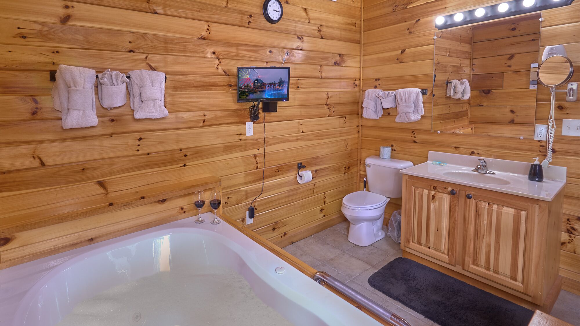 Baño de cabaña de madera con bañera, inodoro, lavamanos y un espejo.