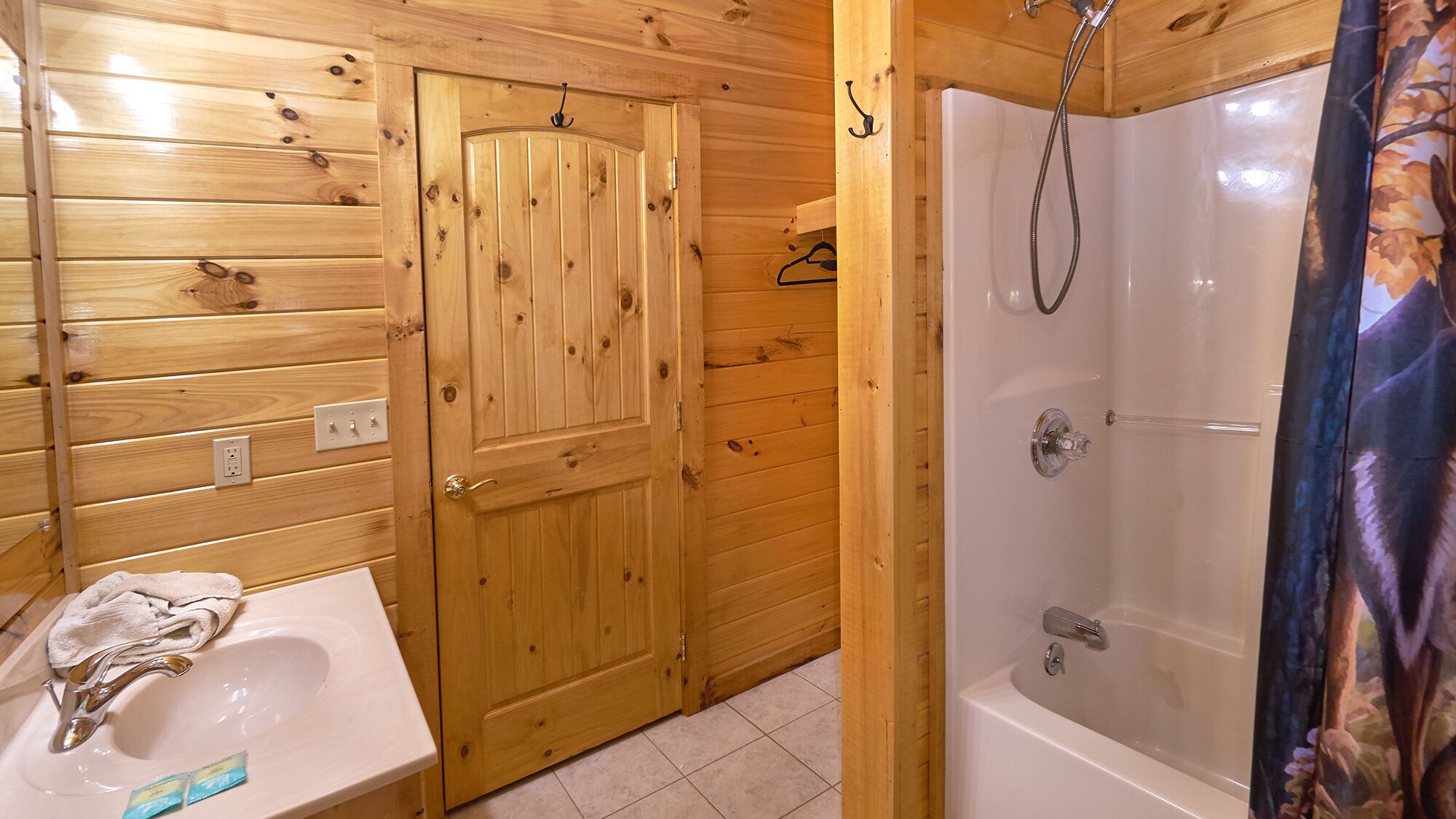 A wooden bathroom with a sink, a shower, and a door.