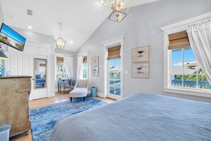 Un dormitorio con una cama grande, televisión, candelabro y vistas al exterior.