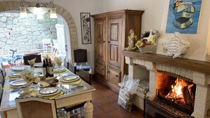 A dining area with a stone wall, wooden cabinet, and a fireplace. - 100 m from the ocean - 8 people (VILA NOVA DE GAIA)