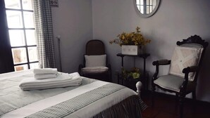 A hotel room with a bed, two chairs, a small table with a vase of flowers, and a window with curtains. - 100 m from the ocean - 8 people (VILA NOVA DE GAIA)