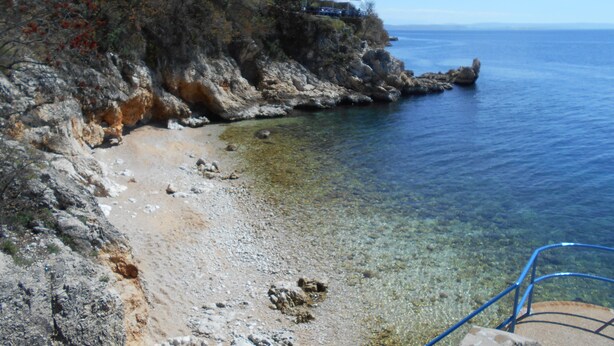 Une plage côtière avec un terrain rocheux et des eaux claires et peu profondes.