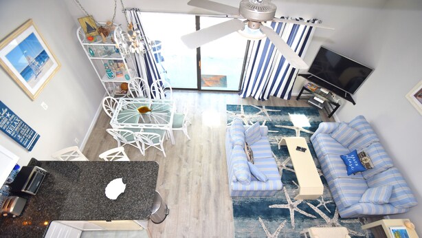 A spacious living room with a large sofa, a dining table, and a TV. - Surfside 60 Unit 303-Oceanside 60th St, Free WiFi, W/D, AC (Ocean City)