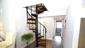 A modern interior with a spiral staircase, a white armchair, and a potted plant. - Surfside 60 Unit 303-Oceanside 60th St, Free WiFi, W/D, AC (Ocean City)