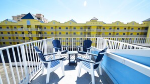 A balcony with white railings and blue chairs, overlooking a yellow building with balconies. - Surfside 60 Unit 303-Oceanside 60th St, Free WiFi, W/D, AC (Ocean City)
