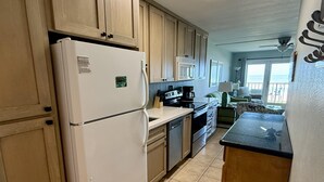 A kitchen with wooden cabinets, a white refrigerator, a microwave, a stove, and a sink.