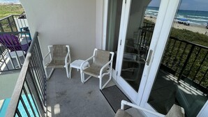 A balcony with white chairs and a pool.