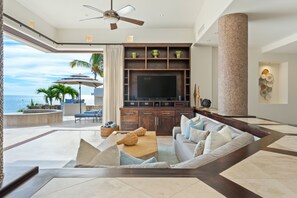 A spacious living room with a large TV, comfortable seating, and a view of the ocean. - Casa Bella 5BR | Unobstructed Ocean Views, Pool & Concierge (San Jose del Cabo)