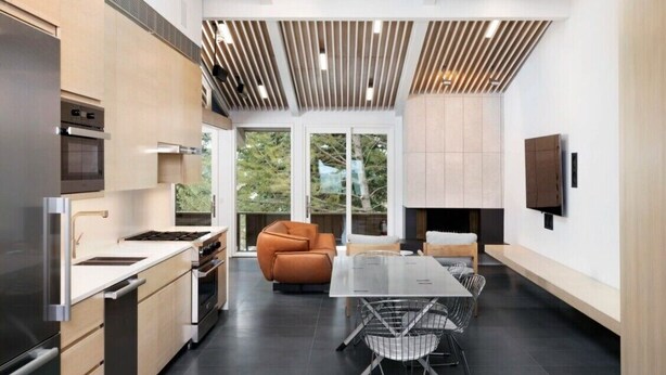 Una cocina moderna con comedor, ventanas amplias y televisor empotrado.