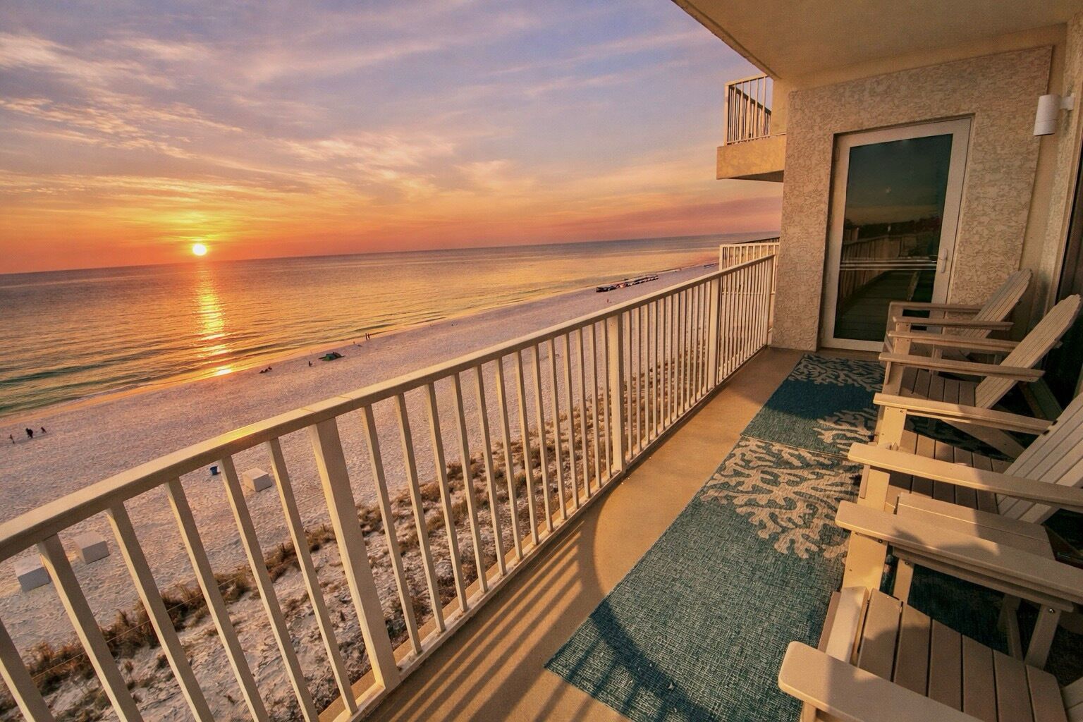 Ein Balkon mit Blick auf Strand und Meer bei Sonnenuntergang.