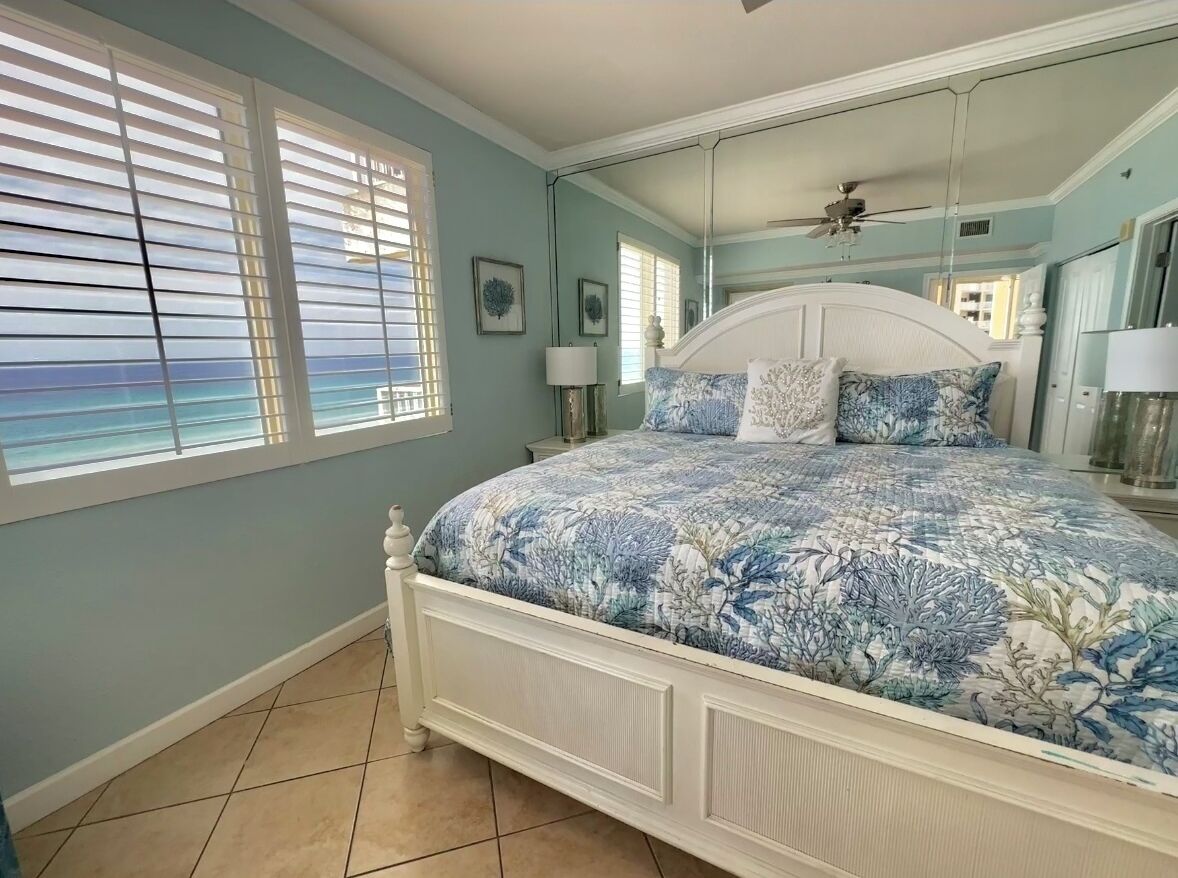 A bedroom with a bed, a ceiling fan, and a window with blinds.
