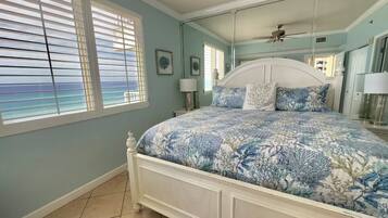 A bedroom with a bed, a ceiling fan, and a window with blinds.