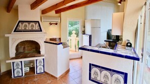 A kitchen with a built-in oven, a sink, and a window overlooking a garden.