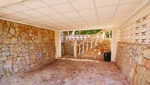 A covered outdoor area with stone walls and a wooden staircase.