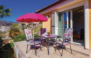An outdoor patio with a table and chairs, a red umbrella, and a view of a building with a tiled roof. - 1 bedroom beautiful apartment in Matulji (Matulji)