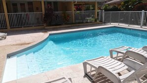 A rectangular swimming pool with clear blue water, surrounded by a white fence and a tiled deck. - Your studio in the Tropics of Martinique. 5 minutes walk from the beach! (Les Trois-Îlets)